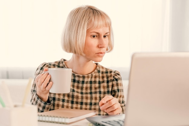 Business woman listening educational lecture on computer\
watching webinar studying on online courses writing notes in paper\
copybook elearning concept