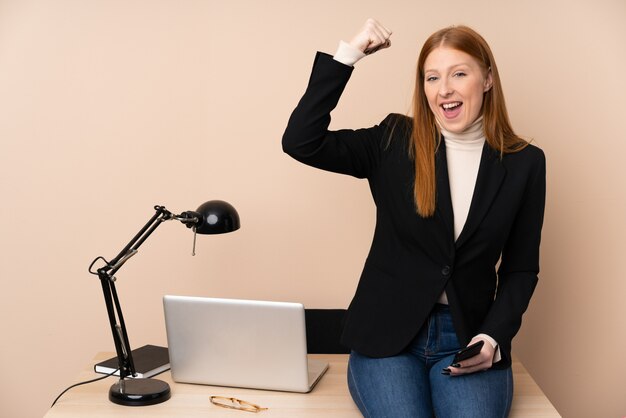 Business woman in a office celebrating a victory