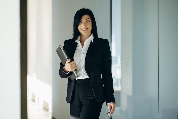 Business woman at the office holding laptop and book