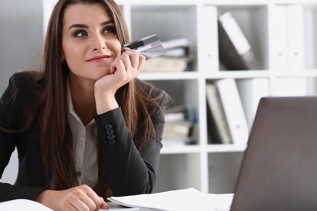 Business woman in the office holds a plastic credit debit card in her hand