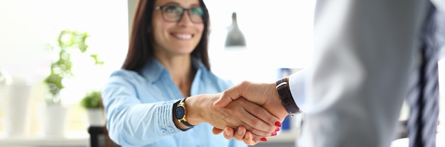 オフィスでのビジネスの女性は、ビジネスパートナーと握手を交わしています。