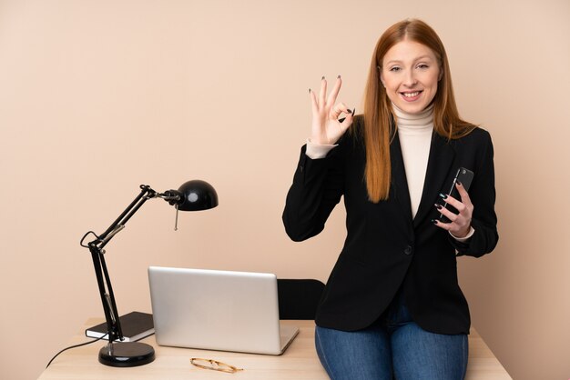 Business woman in a office showing an ok sign with fingers