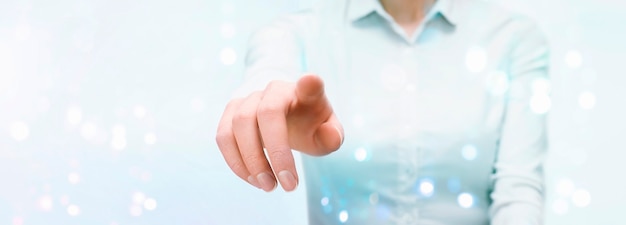 Business woman presses on the touch transparent screen with her
hand. front view.light blue background