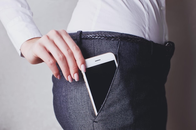 Business woman puts smartphone in the pocket