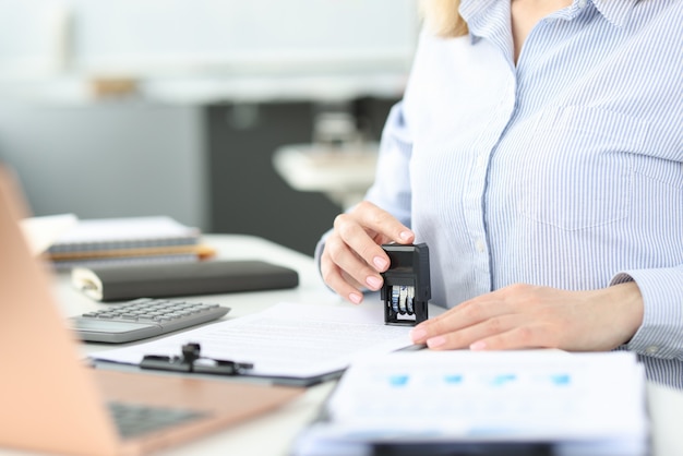 Business woman putting stamp on document in office