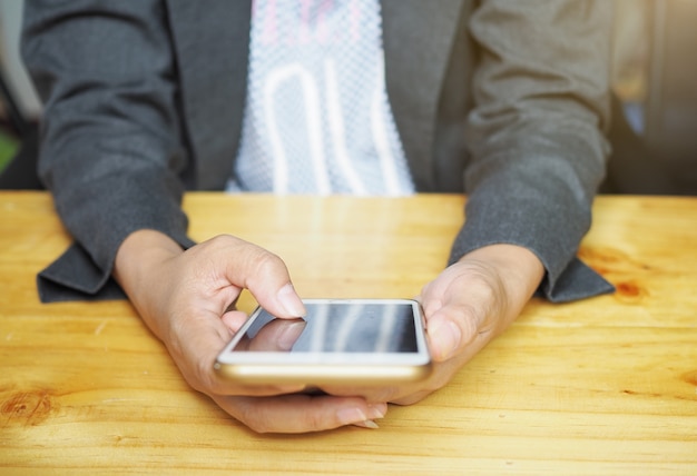 Business woman in read on cell phone, Wood table background.