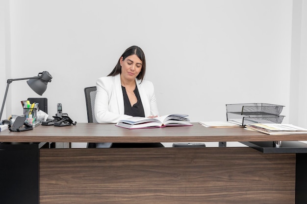 Business woman reading an encyclopedia in her office Woman training at work