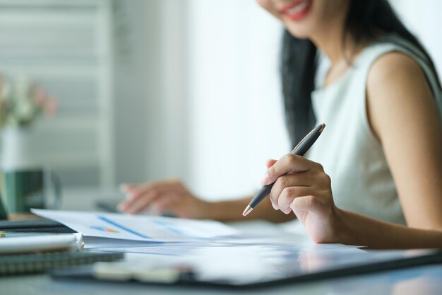 Photo business woman reading information on paperwork and using laptop working on desk