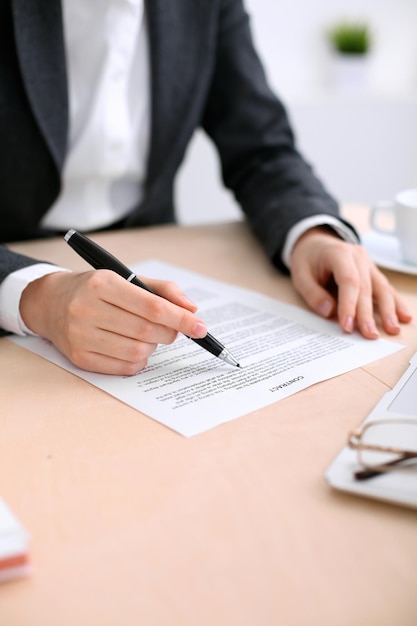 Photo business woman ready to sign a contract while sitting at the table