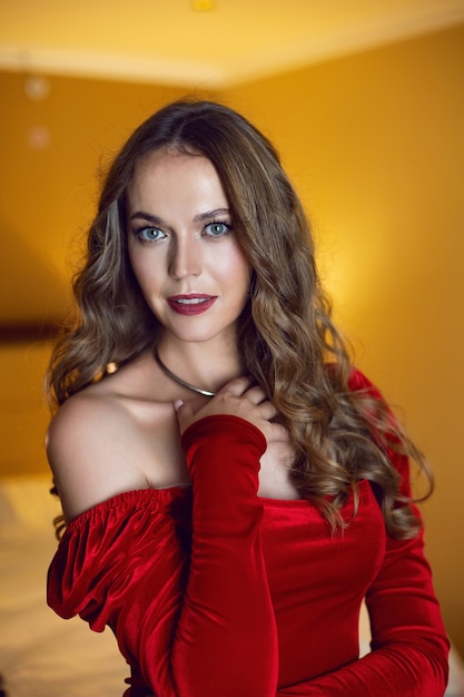 Business woman in a red dress stands the window in a hotel