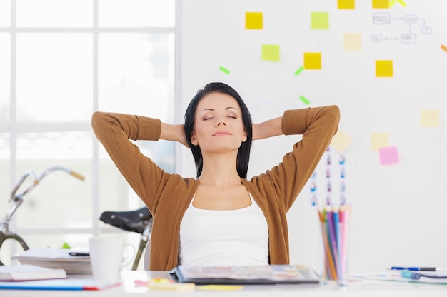 Business woman relaxing. Business woman relaxing with hands behind head and smiling