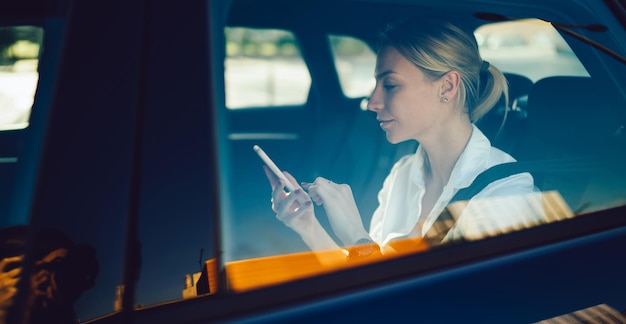 Business woman sending text sms with contract details while getting to destination in car