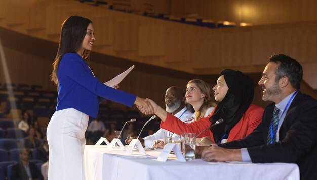 Business woman shaking hand to the business colleague in the auditorium