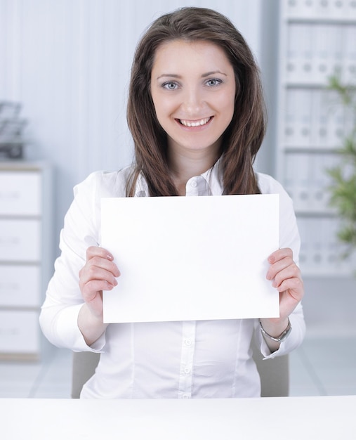 Business woman showing blank sheetsitting behind a Desk