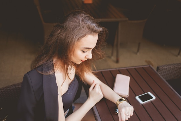 Business woman sitting alone at a restaurant table while looking at clock