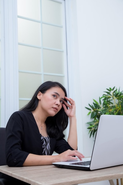 Business woman sitting on chair while thinking looking for ideas in front of laptop