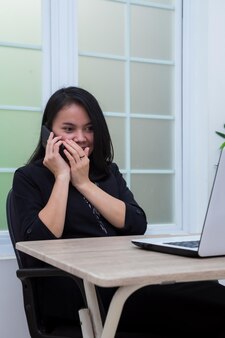 Donna d'affari seduta su una sedia mentre sussurra al telefono davanti a un laptop