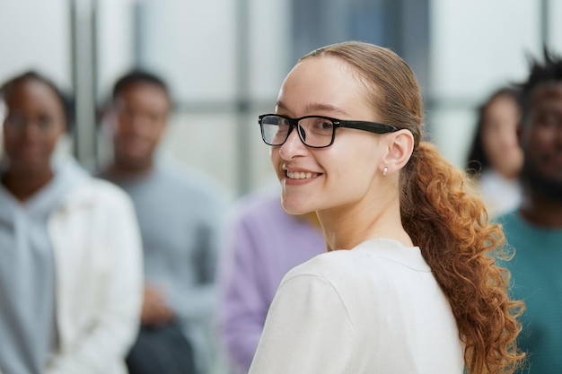 Business woman sitting on a chair with her staff in the background