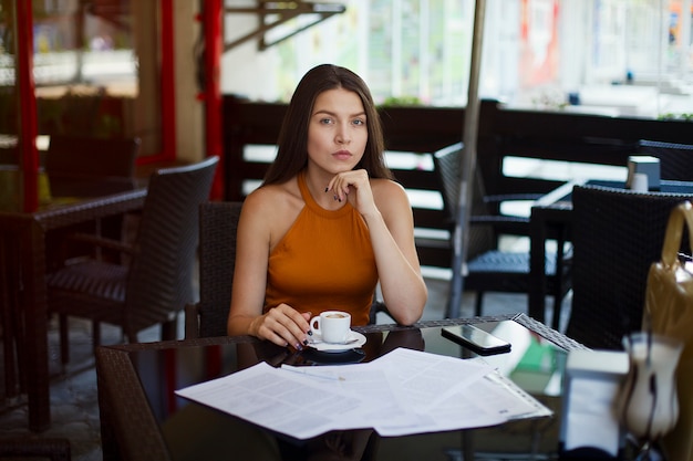 カフェでお茶の上に座っている女性実業家。重要なドキュメントの署名。ビジネスミーティング。