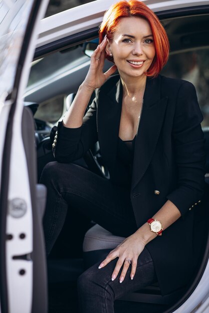 Business woman sitting in electric car at the electric charging station