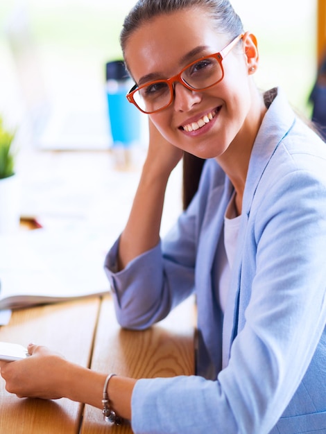Бизнес женщина сидит в своем офисе с помощью планшетного компьютера