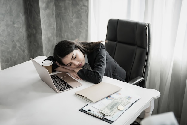 Sonno della donna di affari sul posto di lavoro dello scrittorio dopo il lavoro stanco duro.