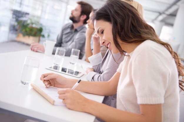 Foto donna d'affari sorriso e scrittura per la riunione diario e copywriter per il progetto di conto in ufficio persona femminile professionale colleghi di lavoro e quaderno per l'azienda lettura e strategia di sala conferenze