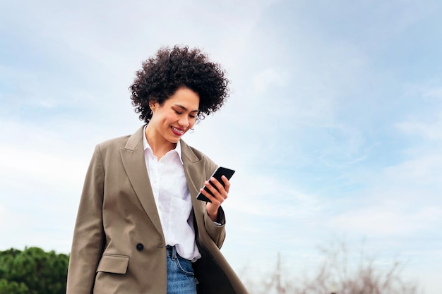 Business woman smiles using a smart phone outdoors