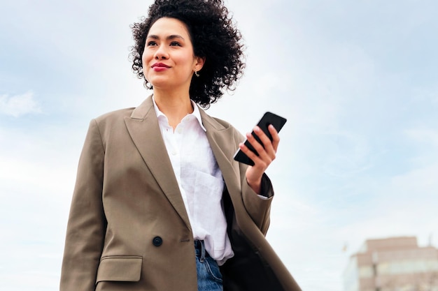 Business woman smiling with a smart phone at hand