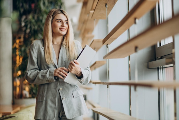 Business woman standing by the window and holding computer