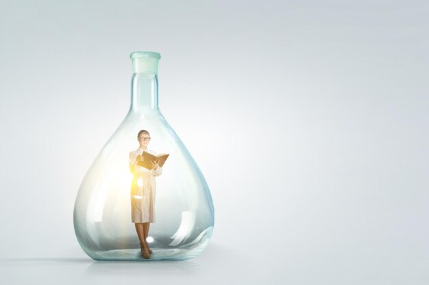 Business woman standing and holding book inside a glass bottle. Mixed media