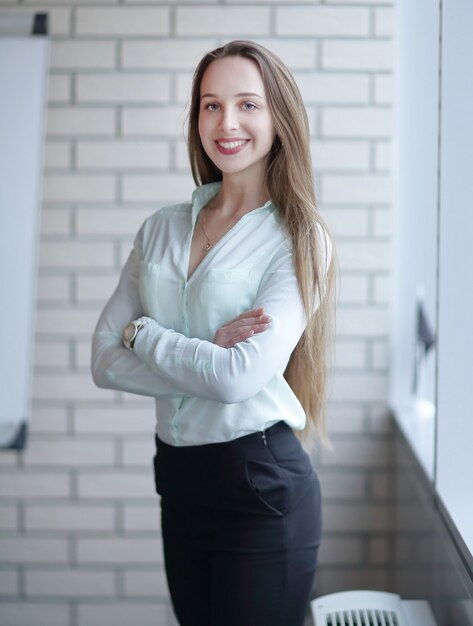 Business woman standing near the window in the corridor of the office.