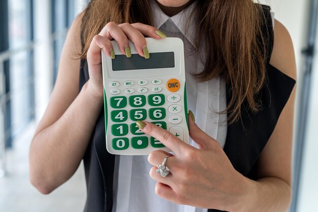 Business woman standing at office and count in calculator