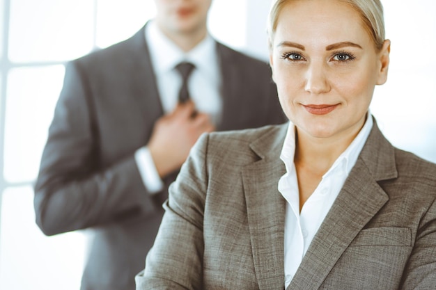 Business woman standing straight with colleague businessman in office, headshot. Success and corporate partnership concept.