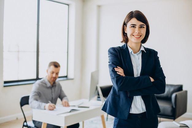 Business woman standing while business partner working on computer