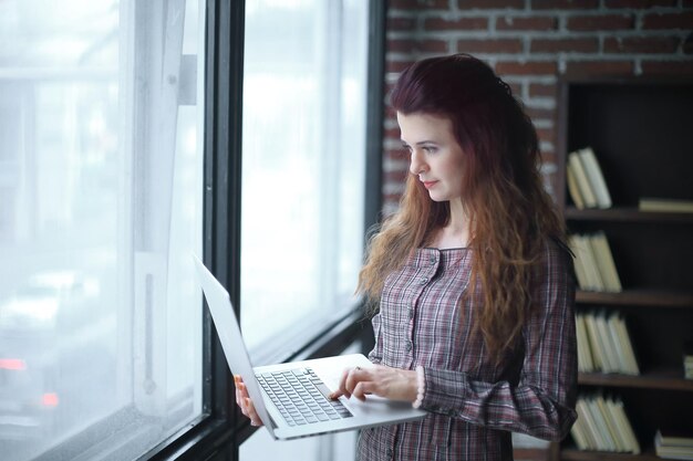 Business woman standing with an open laptop