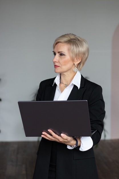 Donna d'affari sta con il computer portatile in ufficio