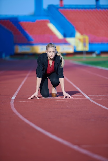 деловая женщина в стартовой позиции готова к бегу и спринту на легкоатлетическом треке