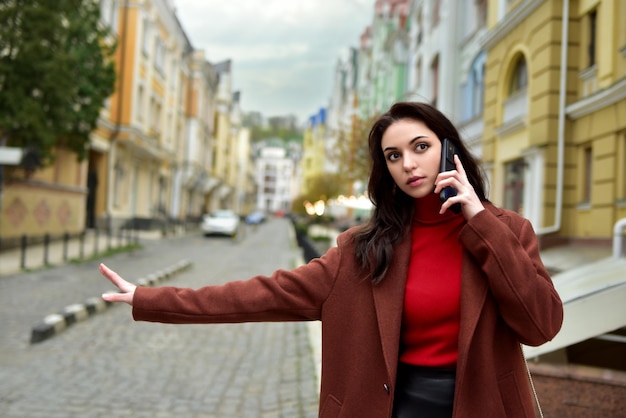 Business Woman on the street talking on the phone while stopping a cab