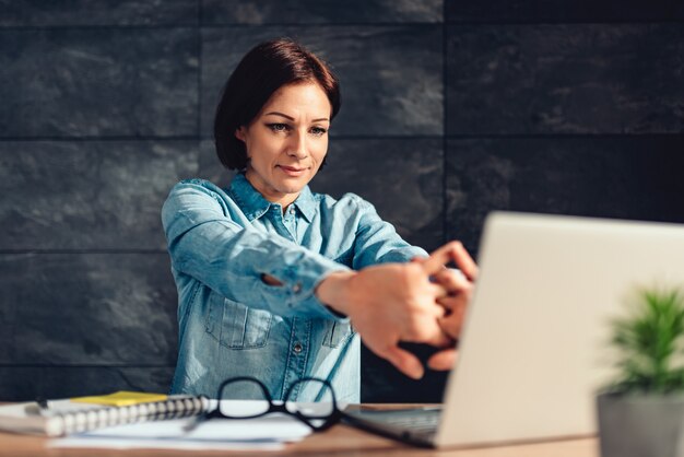 Business woman stretching arms in the office