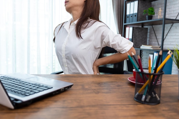 Business woman suffering from back pain in office home