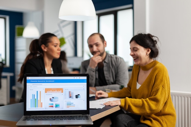 Photo business woman talking about financial project, taking notes, discussing start up ideas using laptop. diverse employees gathered in co-working, working process in busy company, teamwork help concept