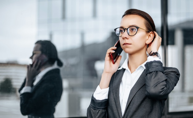 A business woman talking on the phone in the city during a working day waiting for a meeting