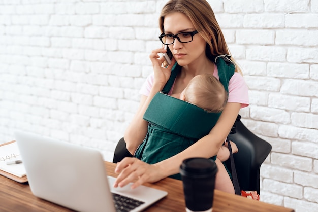 Business woman talking phone and holding newborn