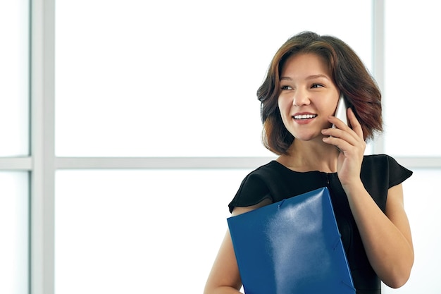 Business woman talking on the phone Portrait of beautiful girl in office on white background