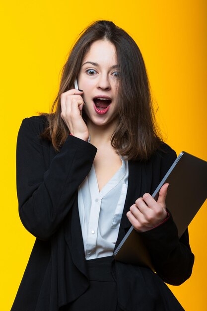 Business woman talking on the phone on a yellow backgroundStudio business shooting