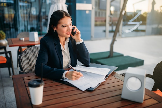 Business woman talks by mobile phone in cafe