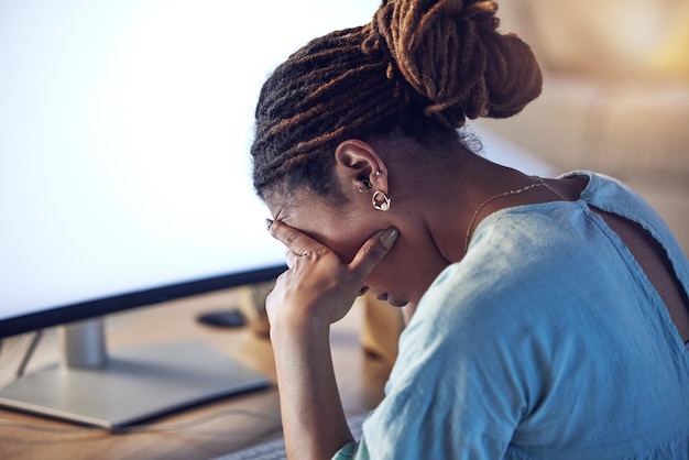 Photo business woman tired and stress at computer in an office at night while working late on deadline african entrepreneur person with hands on head for pain burnout or depression and fatigue at work