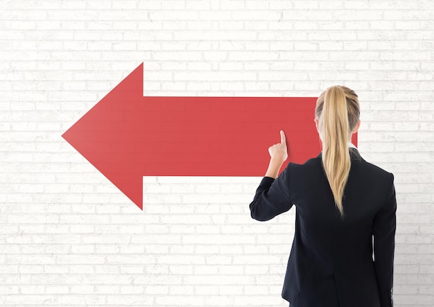 Photo business woman touching a red arrow against white wall