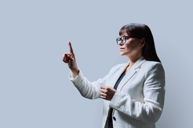 Business woman touching with finger on virtual screen grey background